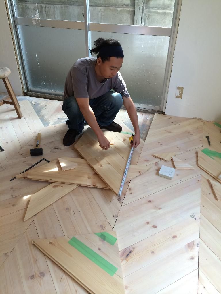 A craftsman carefully laying new herringbone wood flooring