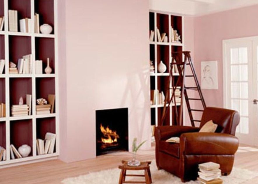 A cosy reading room with built-in shelves, a fireplace and a leather armchair
