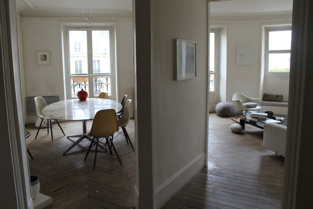 Open rooms with herringbone wood floors, a round dining table and a sitting area